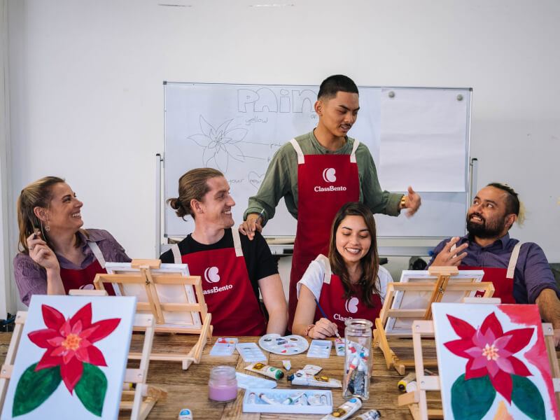 A group of people wearing aprons at Christmas paint and sip class